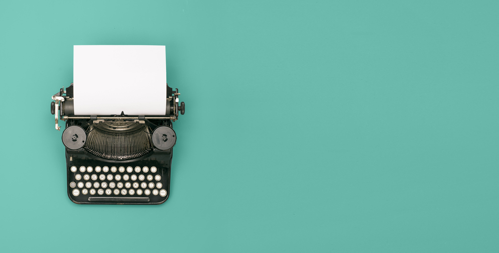 Old school black typewriter with paper in reel.