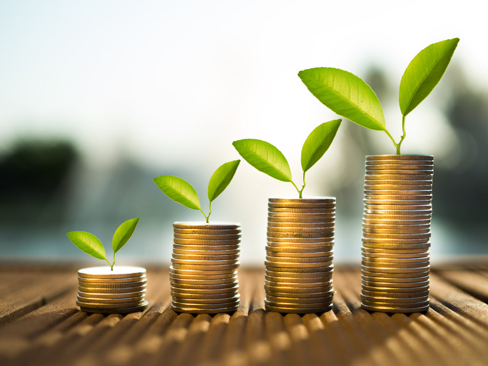 Stacked columns of quarters with little green plants growing on top of them.