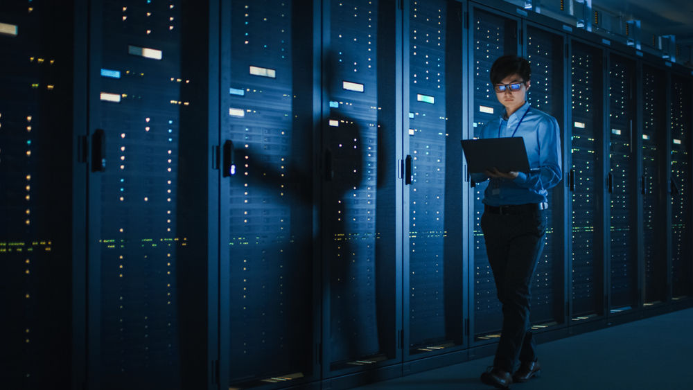 A professional monitoring a series of large, dark mainframe computers.