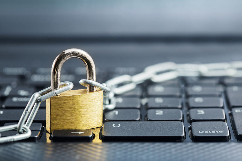 A computer keyboard with a padlock and chains resting on it.