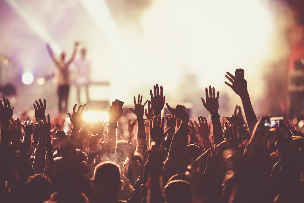 A concert with audience raising their hands in the air.