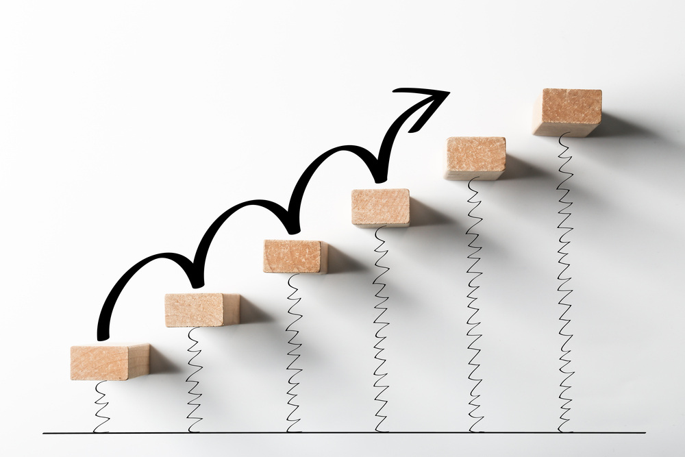 Concept of growth using a sequence of blocks forming stairs with an arrow.